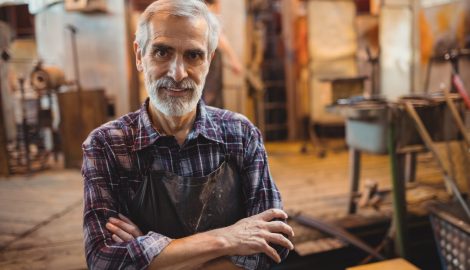 Portrait of glassblower standing with arms crossed at glassblowing factory