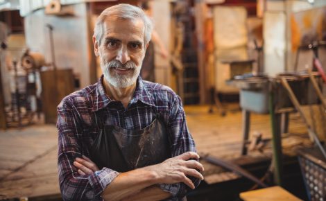 Portrait of glassblower standing with arms crossed at glassblowing factory